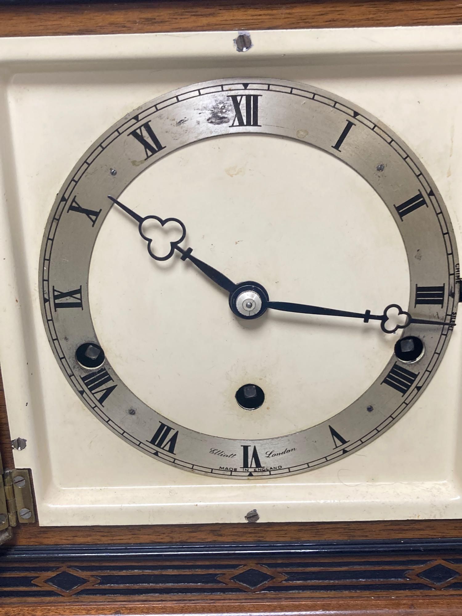A mahogany mantel clock with ebonised decoration, by Elliott of London, width 33cm, height 25cm